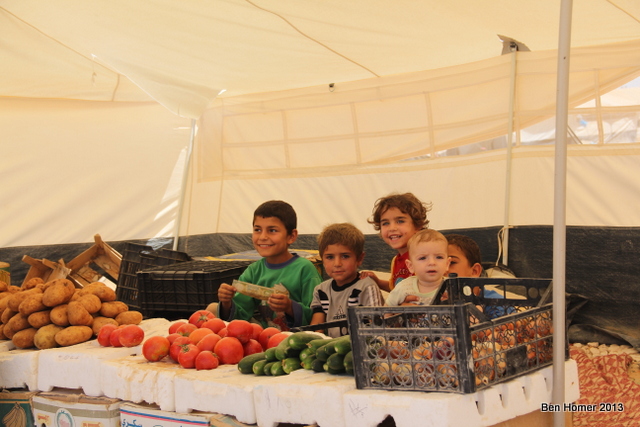 Children selling vegetables at a family-run stand inside Za’atari. An internal economy has developed in the camp. Nearly anything can be purchased with Syrian money. 